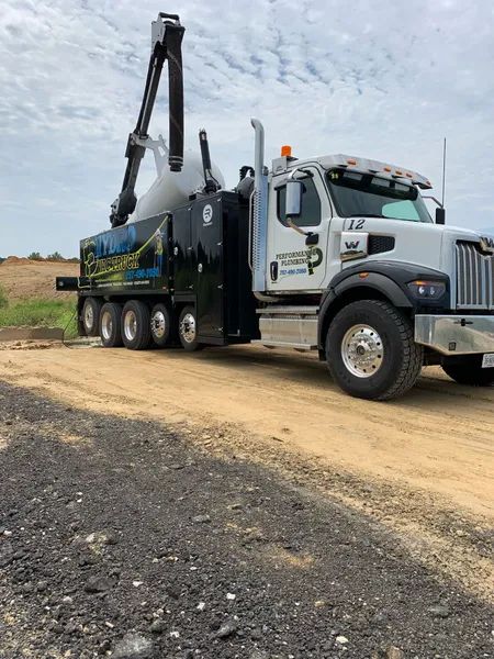 White tow truck with raised crane on a dirt road in a rural area