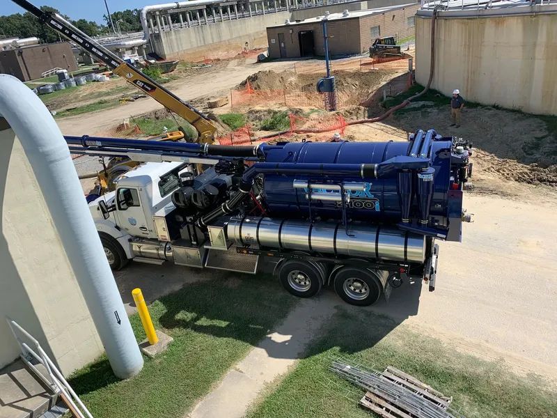 Blue drilling truck on a construction site beside a concrete wall and dirt excavation