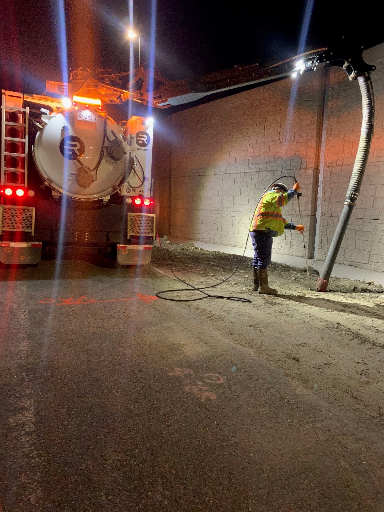Worker in a high-visibility jacket inspecting a snow-dusted truck at night under streetlights.