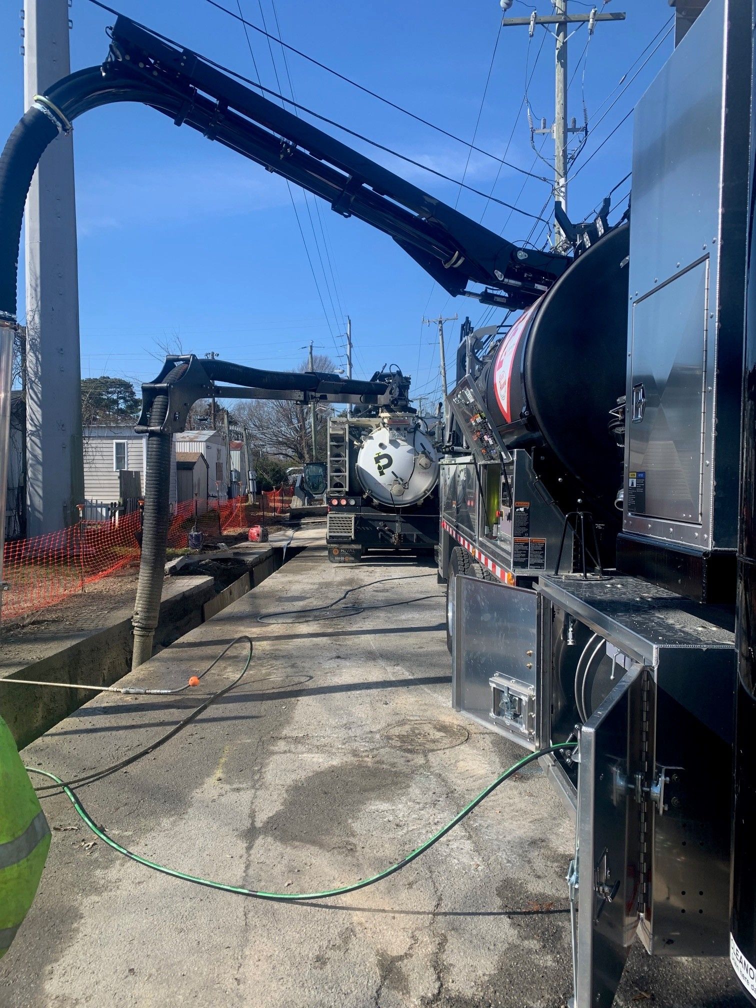 Industrial equipment with large blue hoses along a narrow concrete walkway under a bright sky
