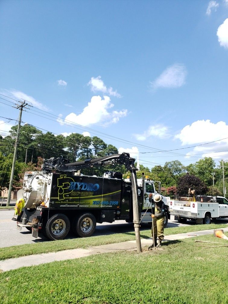 Utility truck and workers on a roadside under a blue sky, with a white pickup nearby.