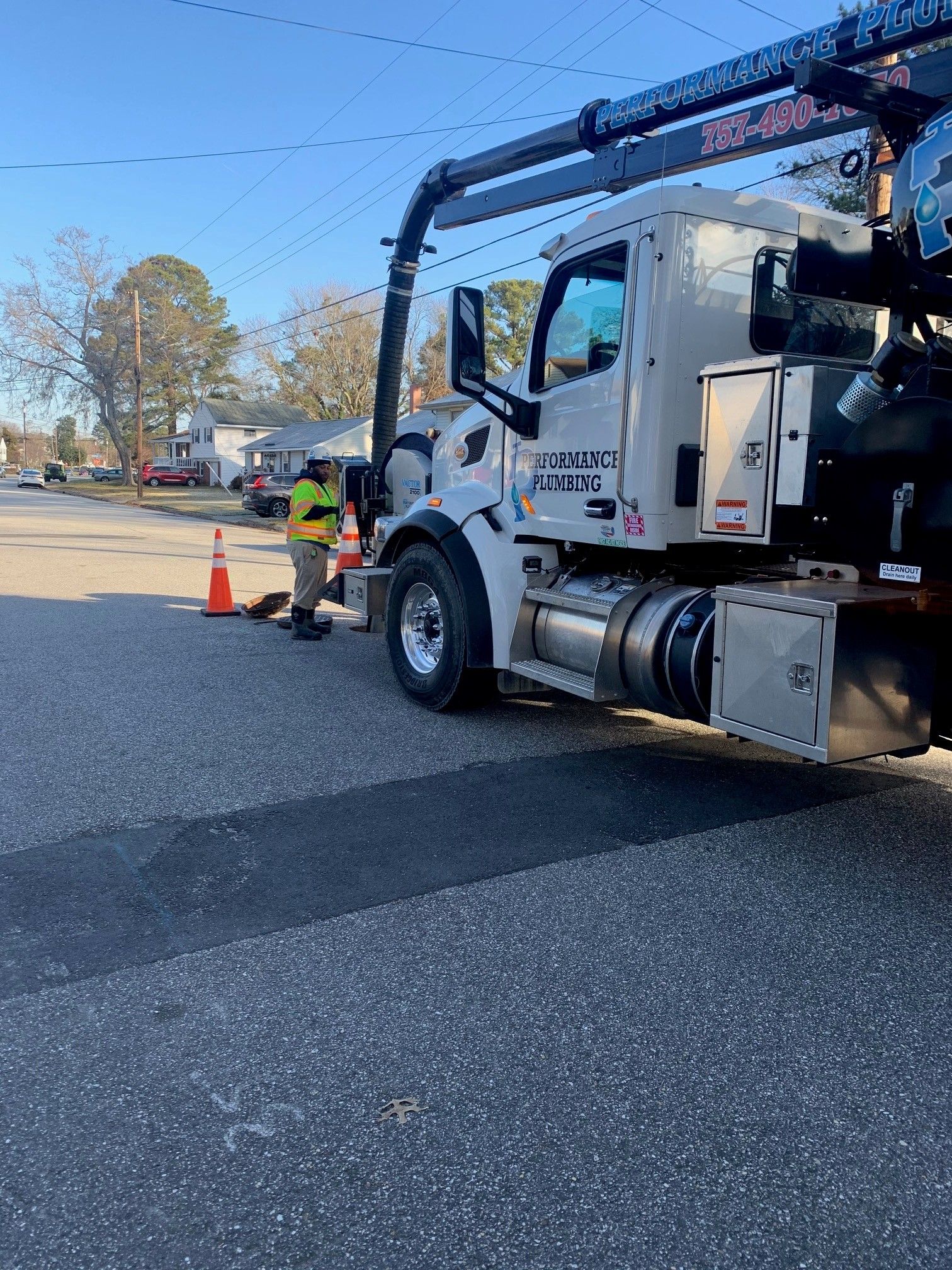 Tow truck and worker beside orange cones on a road in daylight