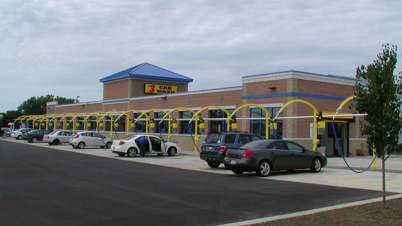 Shopping center storefront with yellow arches, blue roof, and parked cars in front