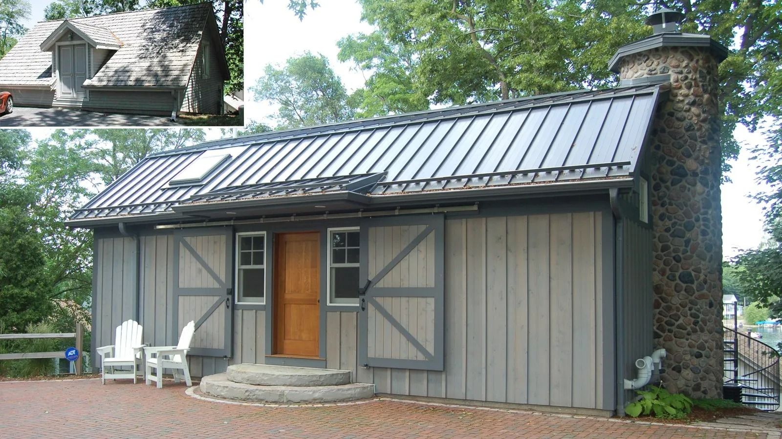 Small rustic cabin with gray siding, metal roof, wooden door, and stone chimney in a wooded yard