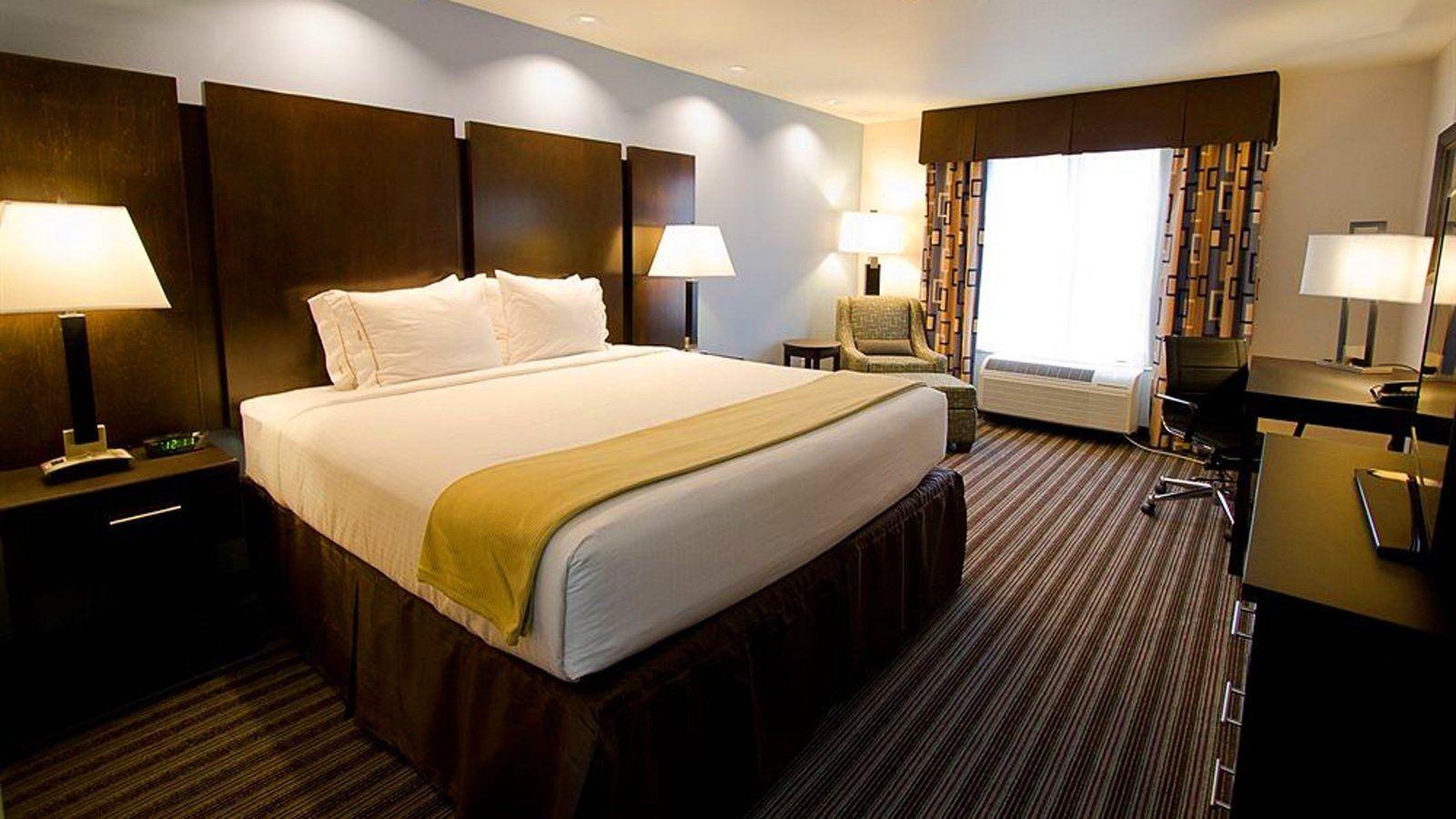 Hotel room with two queen beds, warm lamps, and a large window with curtains