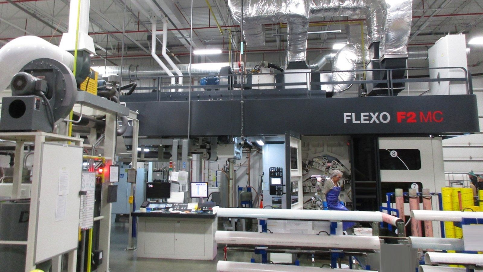 Industrial print production floor with a large FLEXO machine and workers in the background