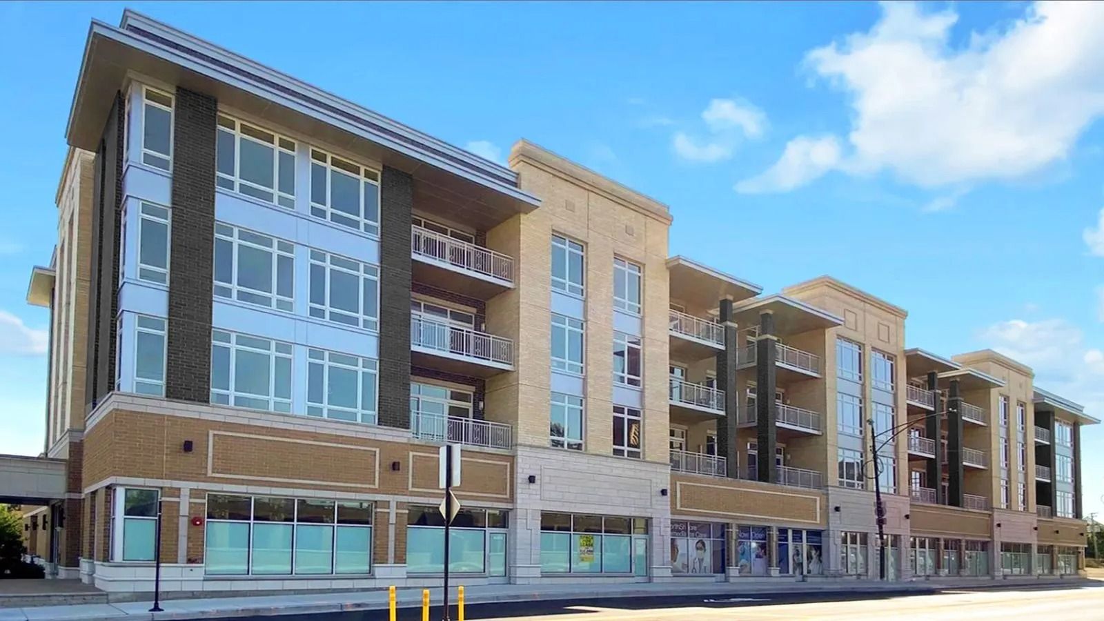 Modern multi-story apartment buildings with storefronts on the ground floor under a blue sky.