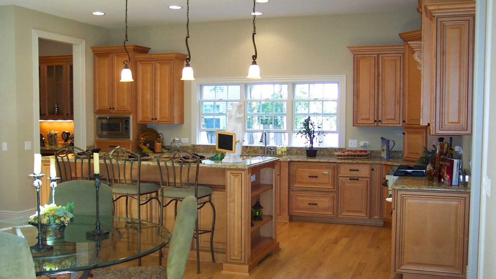 Bright kitchen with wooden cabinets, island seating, and sunlight through a window