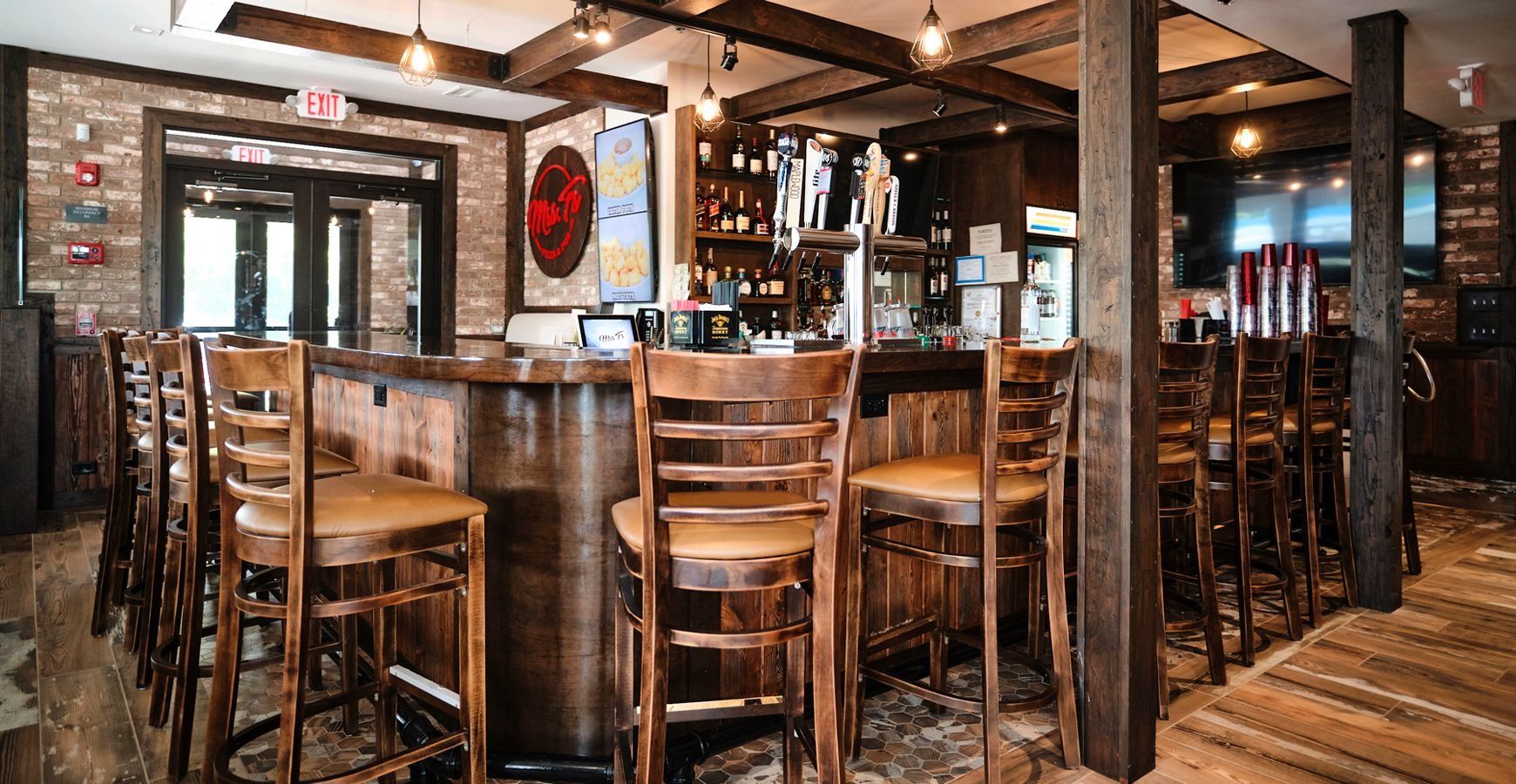 Rustic bar interior with wooden tables, stools, exposed beams, and warm lighting