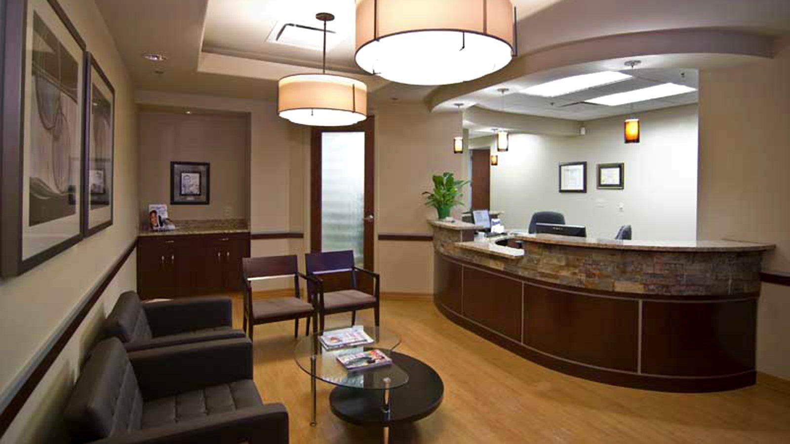 Modern lobby with curved reception desk, seating area, and hanging lights in a beige interior.