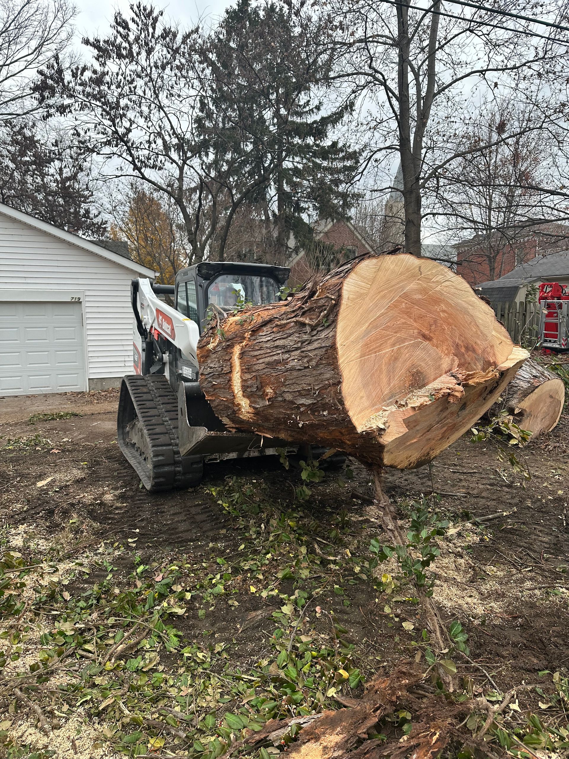 A bulldozer is carrying a large log in a yard.