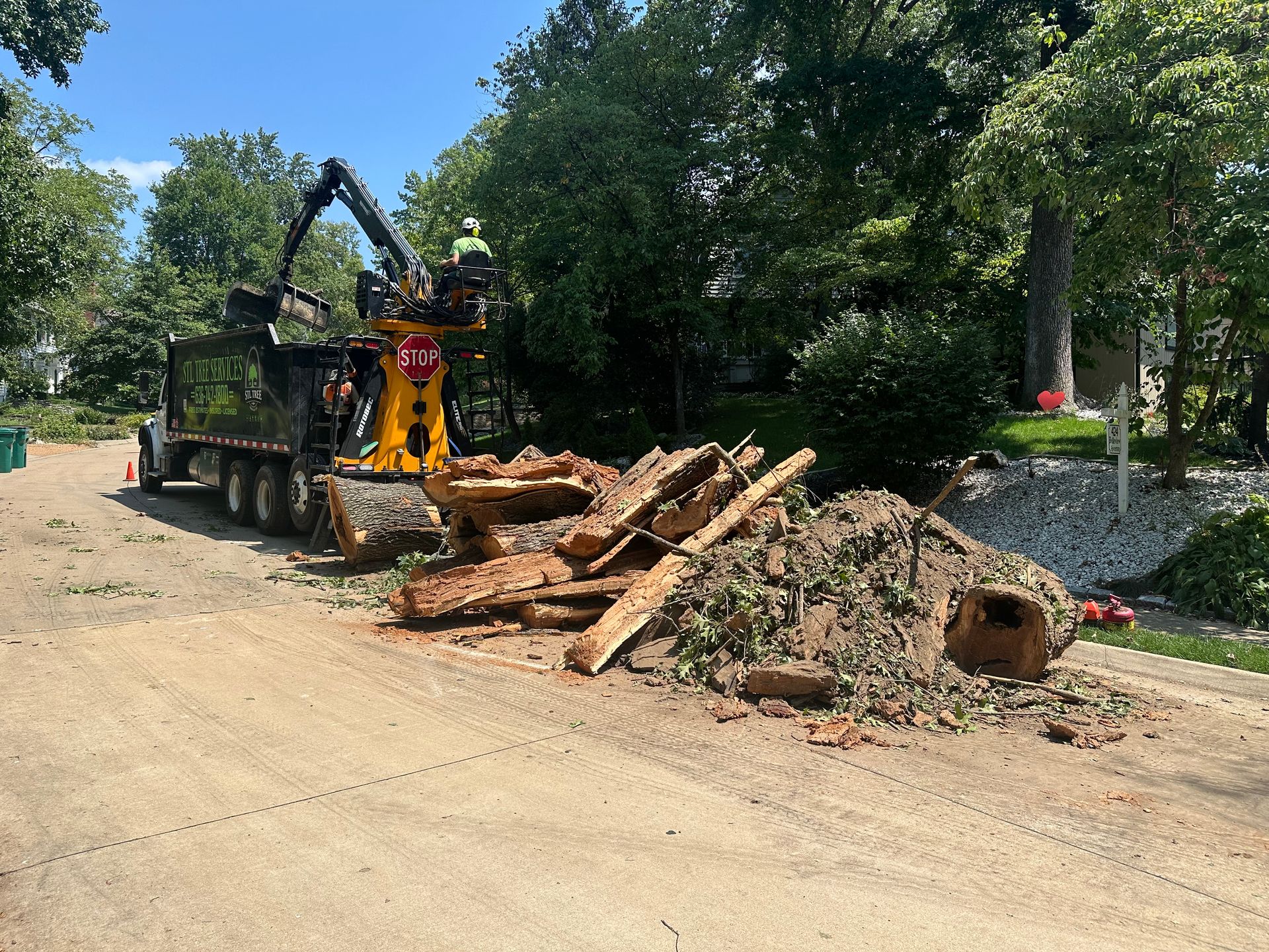 A pile of wood is sitting on the side of the road next to a dump truck.