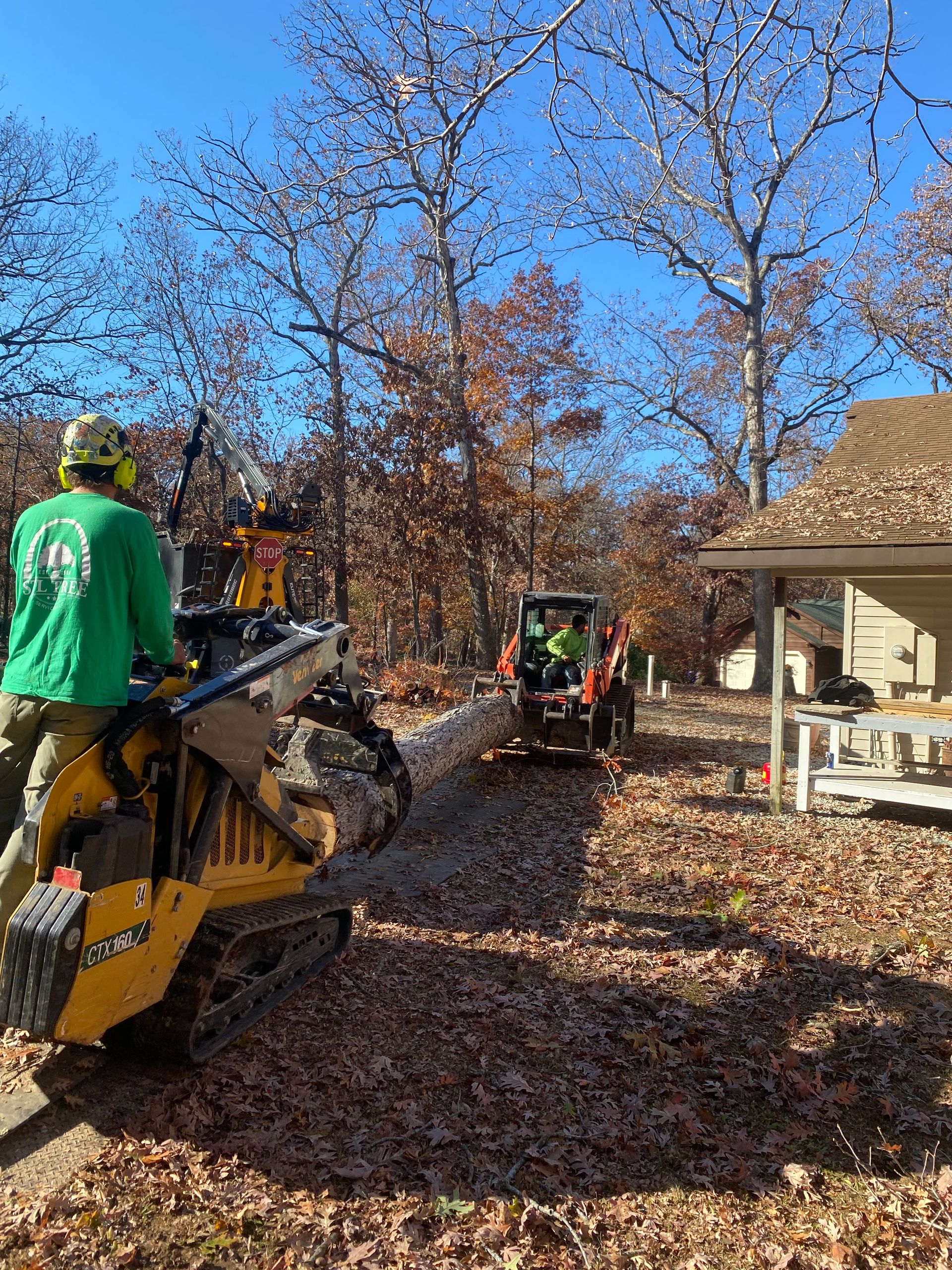 A man is riding a bulldozer in a driveway next to a house.