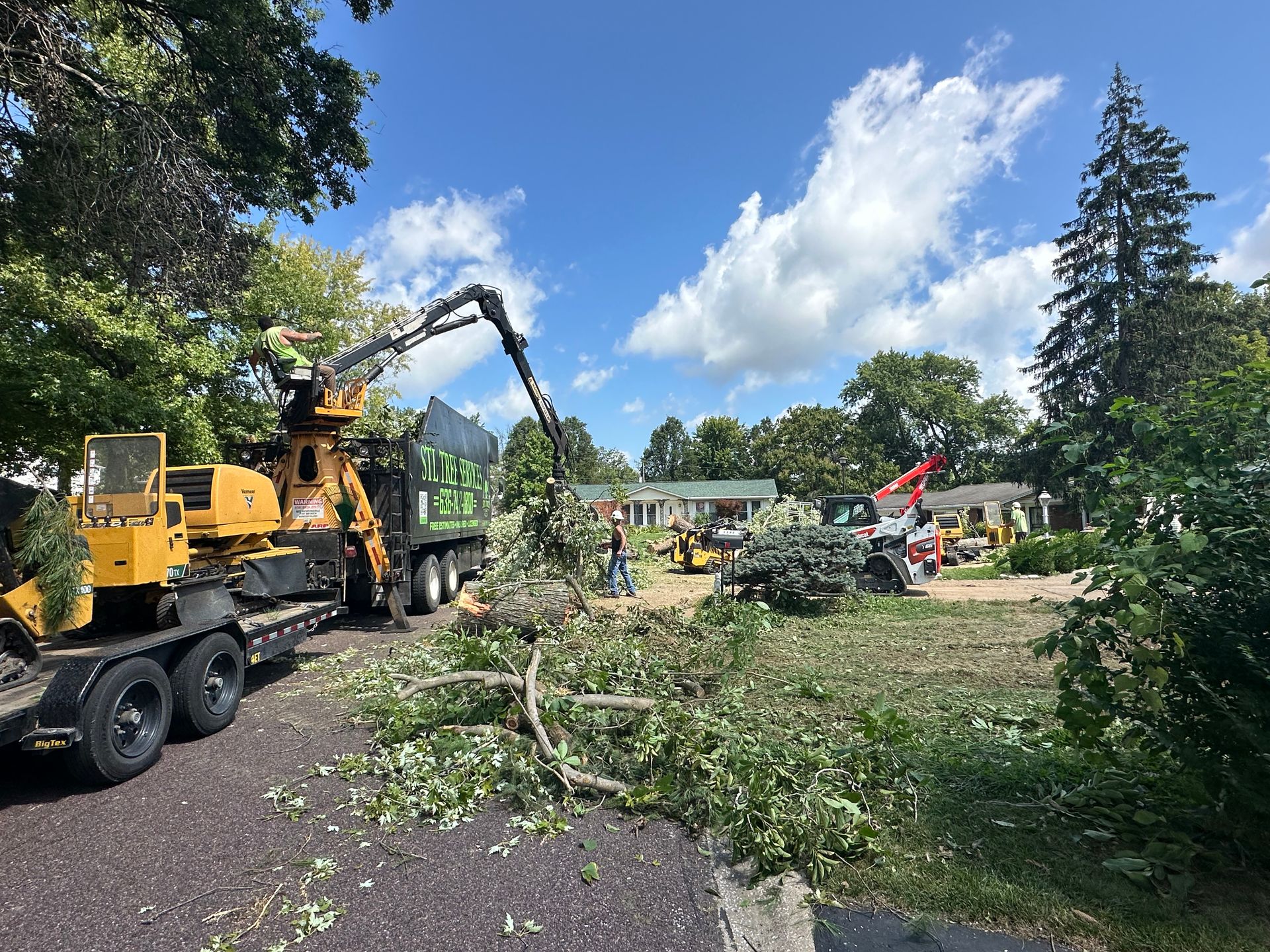 A tree chipper is cutting down a tree in a yard.