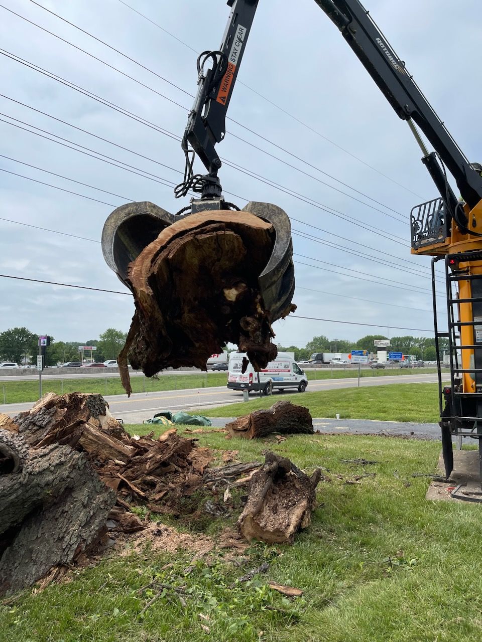 A large tree stump is being lifted by a crane.