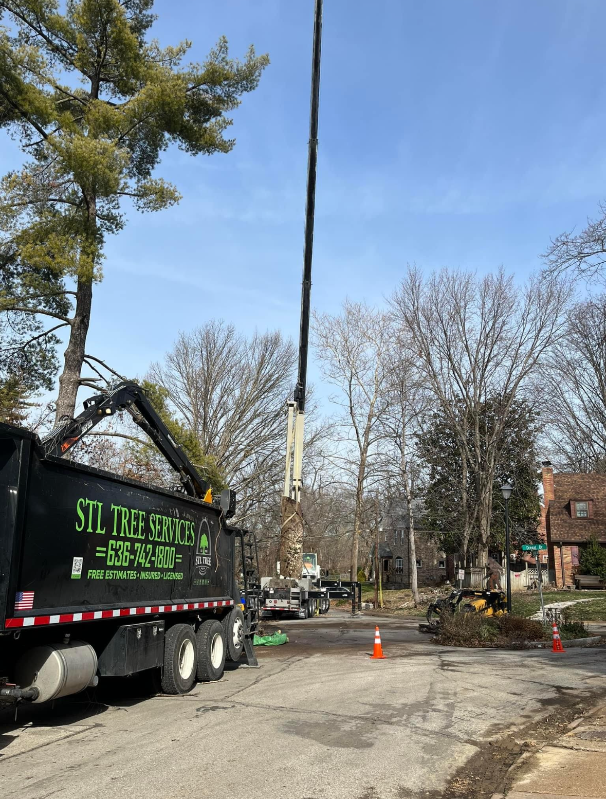 A dump truck with a crane attached to it is parked on the side of the road.