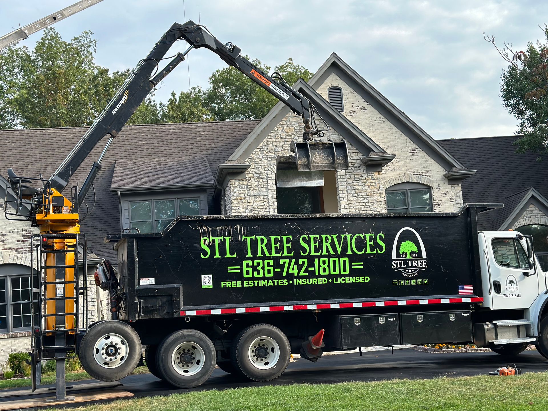 A stl tree services dump truck is parked in front of a house