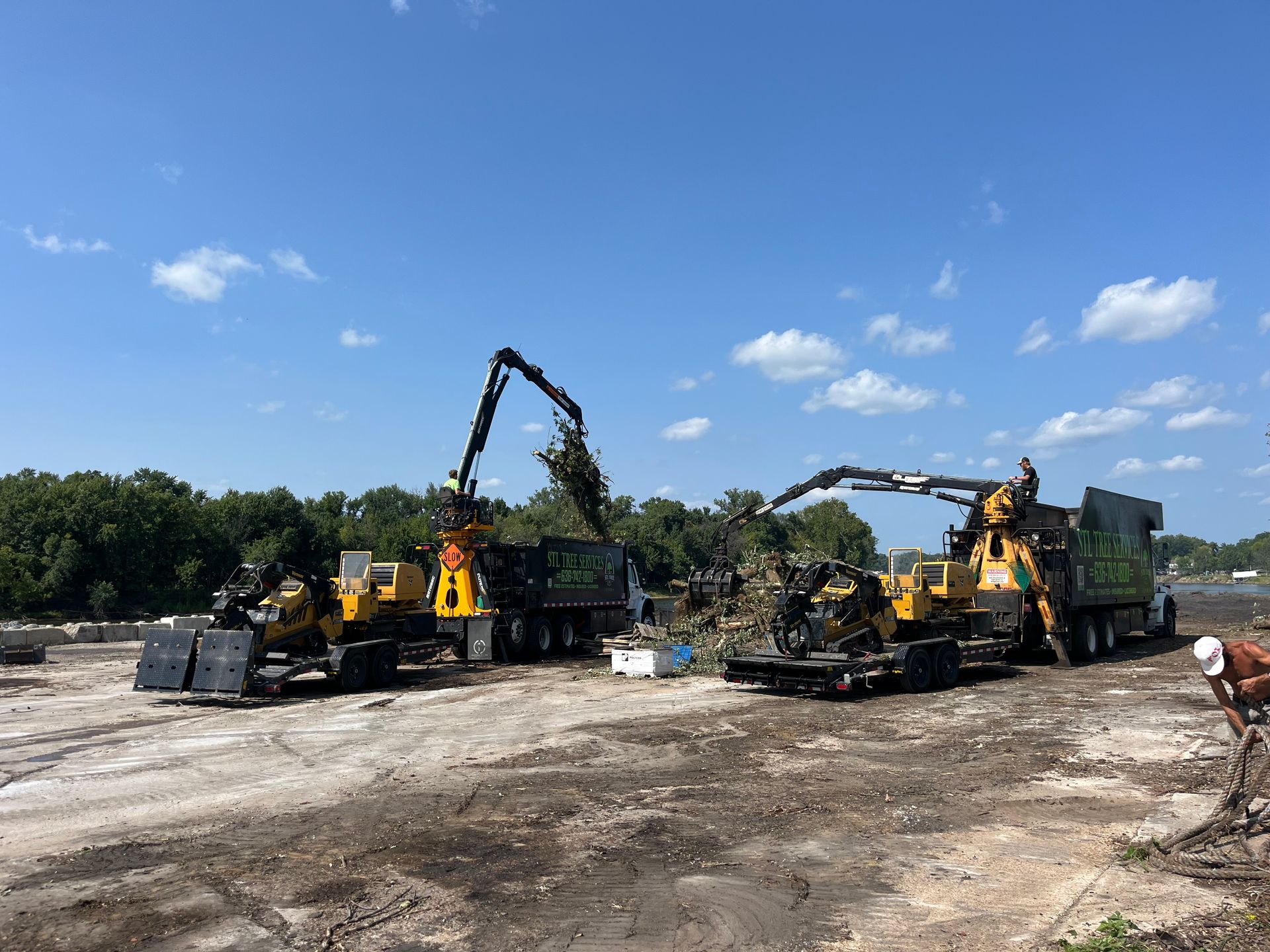 A group of construction vehicles are parked in a dirt field.