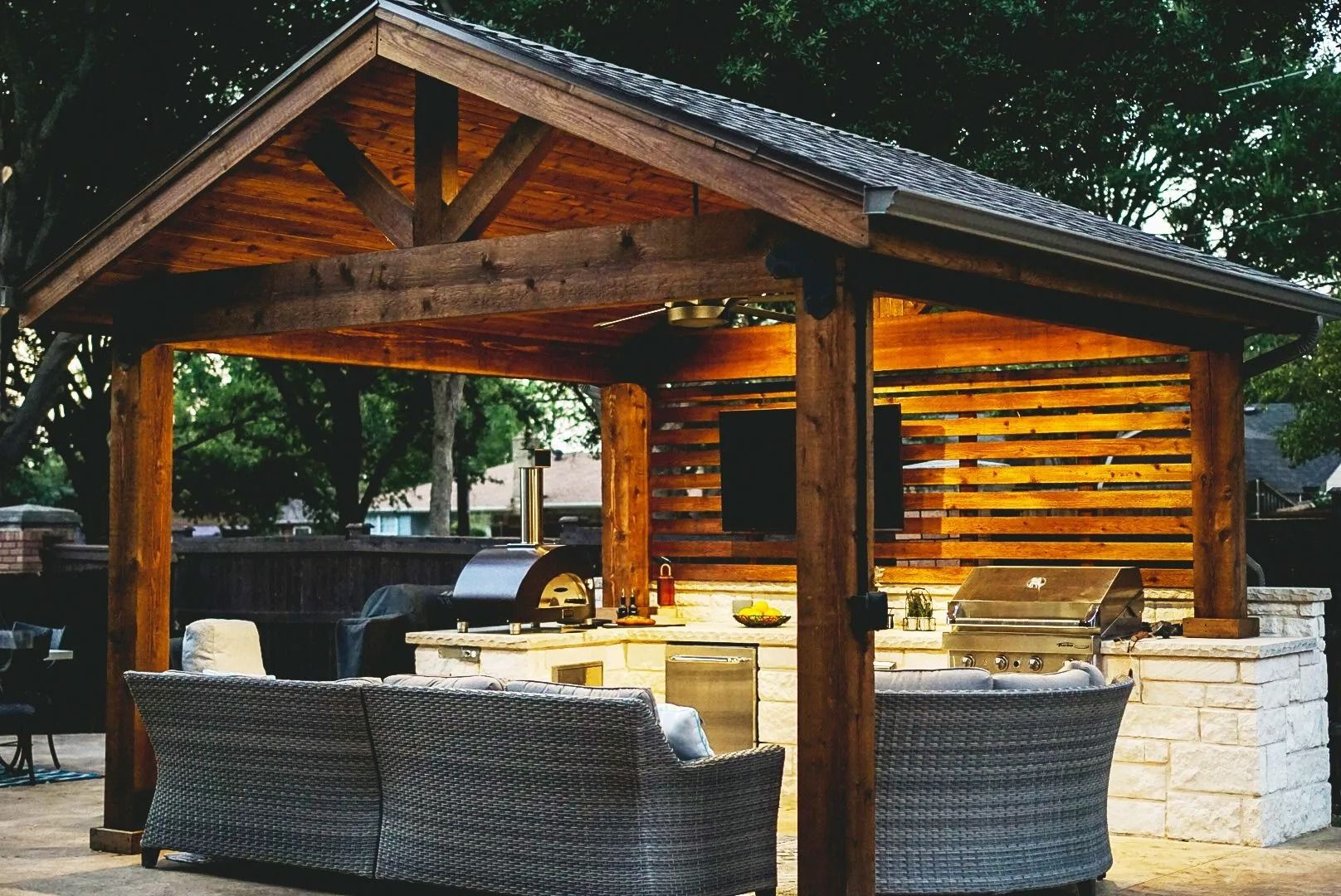 Cozy wooden outdoor pavilion with wicker seating and warm lights at dusk