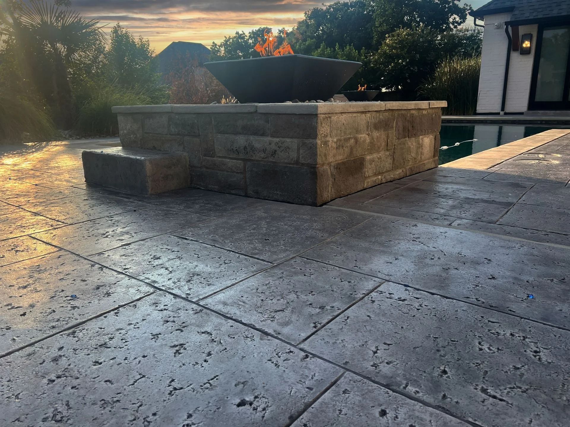 Stone patio with a raised rectangular planter and fire pit