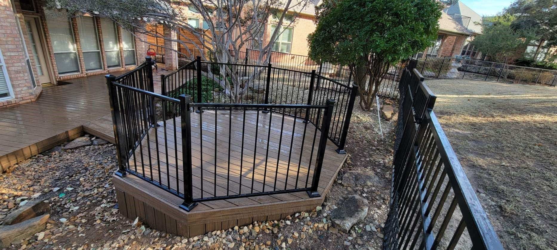 Black metal fence around a raised octagonal garden bed in a leaf-covered yard
