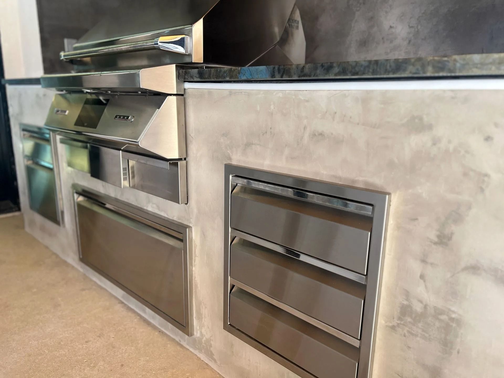 Stainless-steel built-in oven and warming drawers in a modern kitchen wall