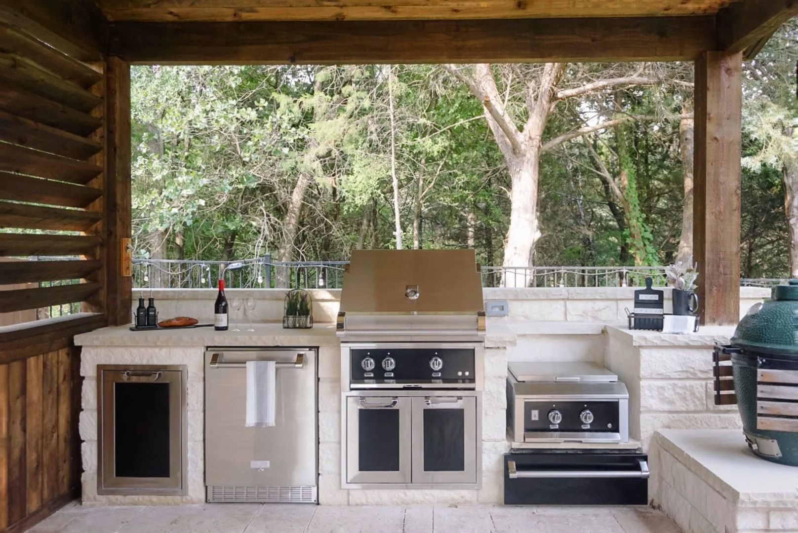 Outdoor covered patio with built-in stainless steel grills and counters under a wooden roof