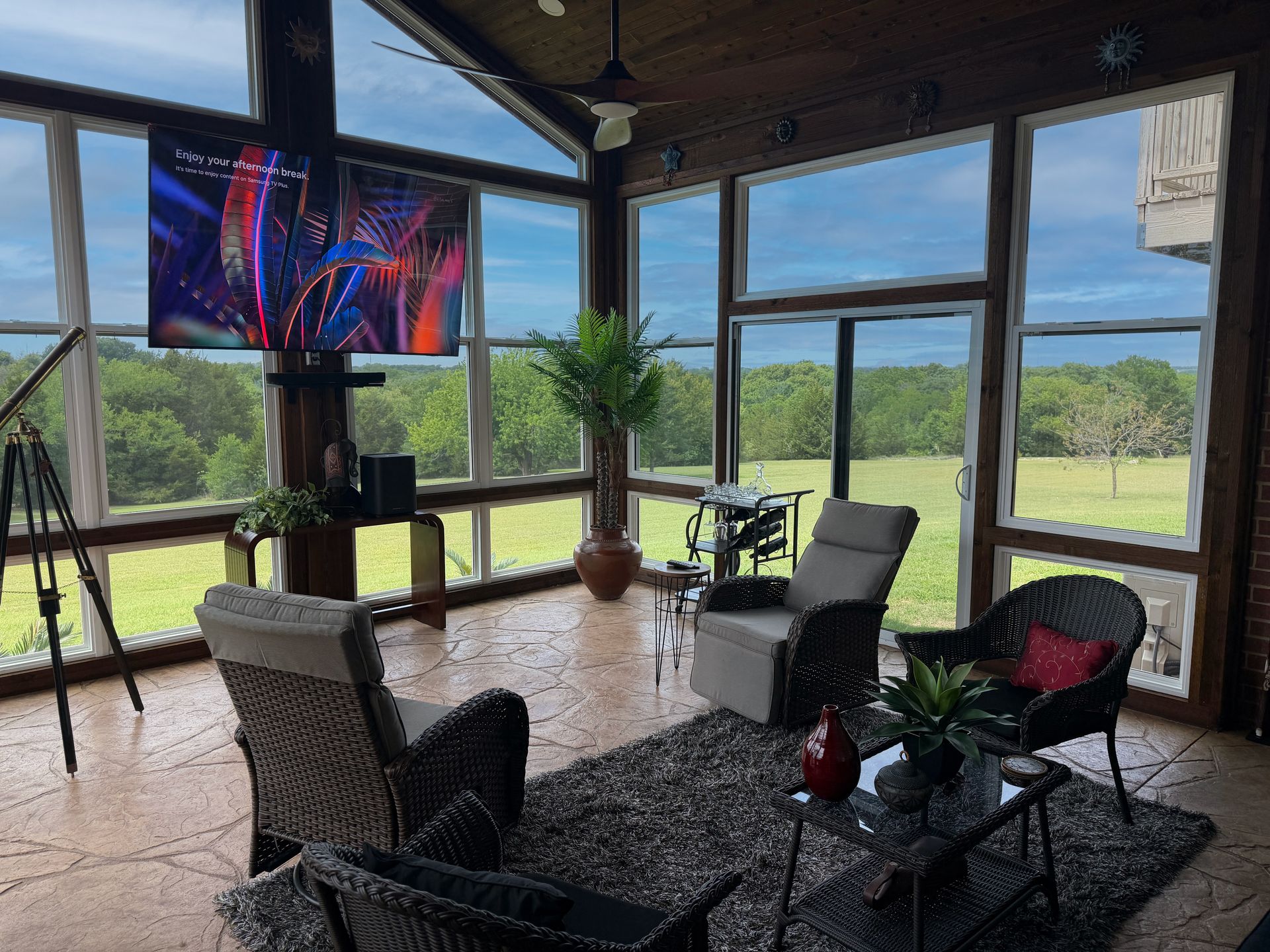 Screened patio with chairs, table, TV, and large windows
