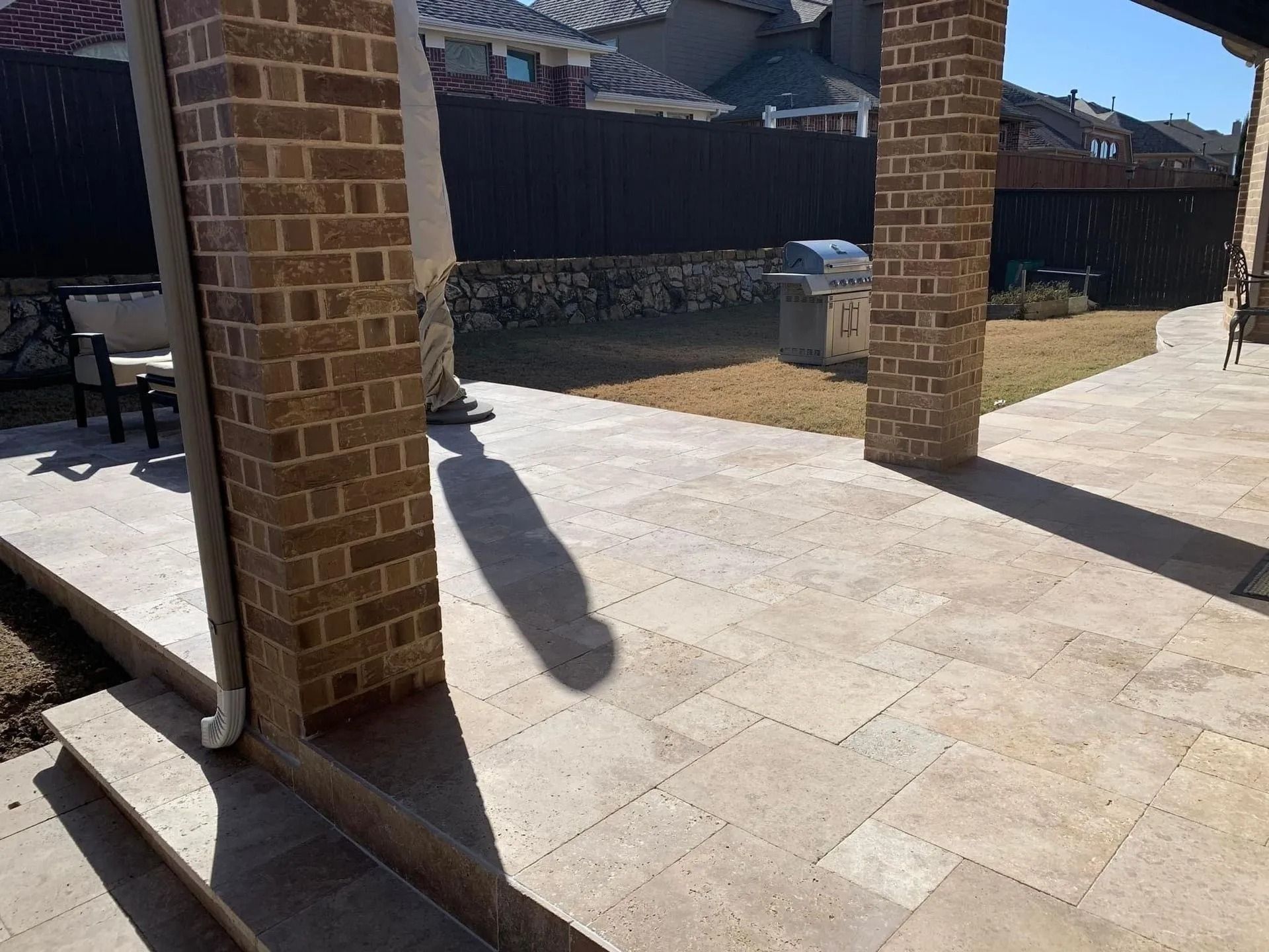 Brick patio with covered columns and long shadows in bright sunlight
