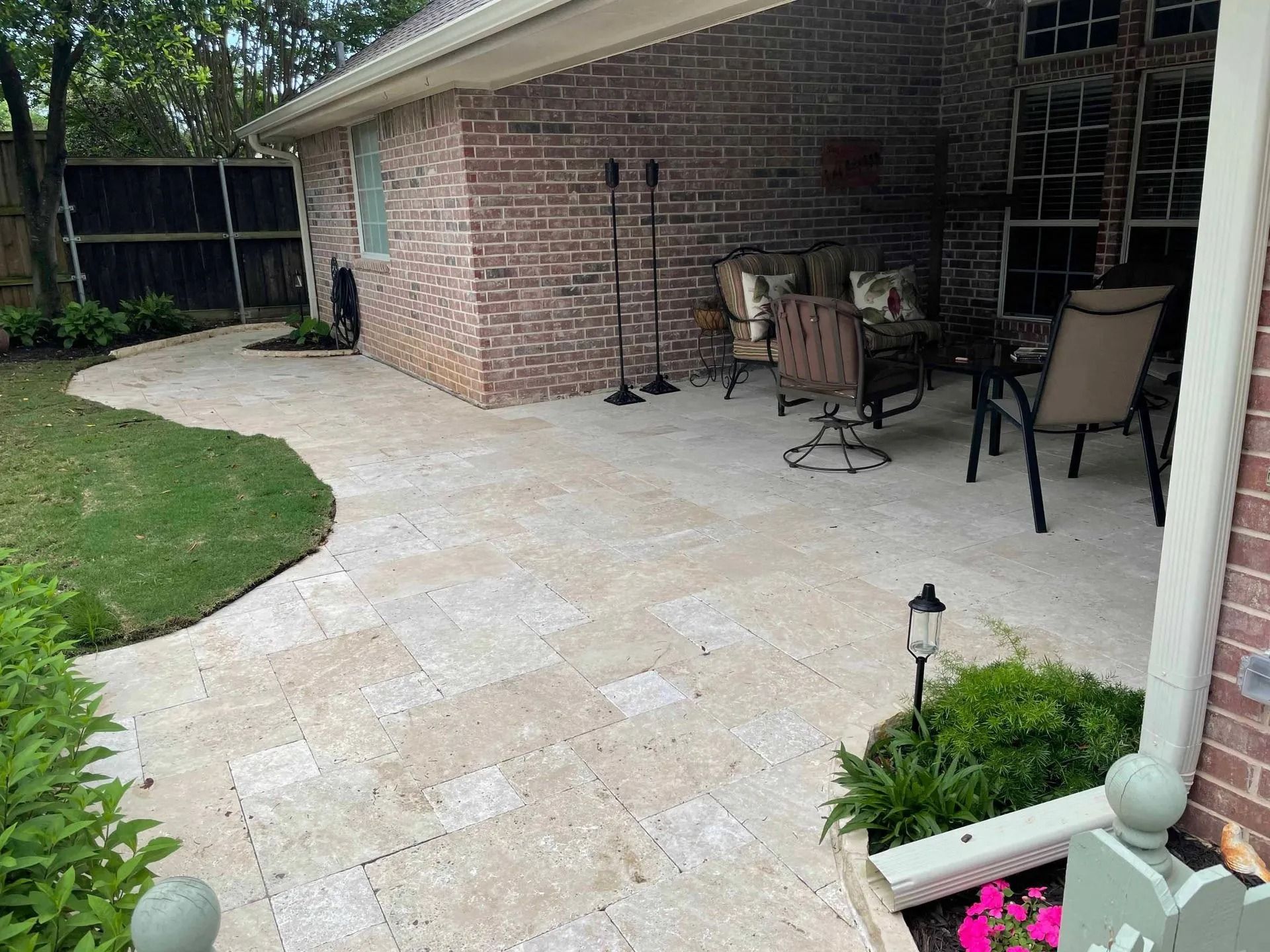Brick patio with stone pavers, outdoor dining chairs, and a curved walkway beside a house
