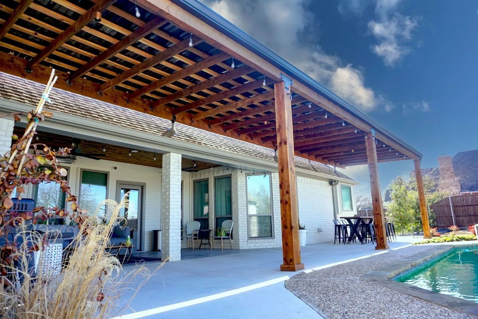 Modern patio with wooden pergola, pool, and sliding glass doors