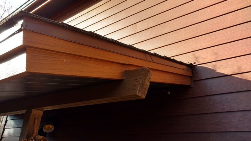 Wooden overhang attached to a brown house siding.