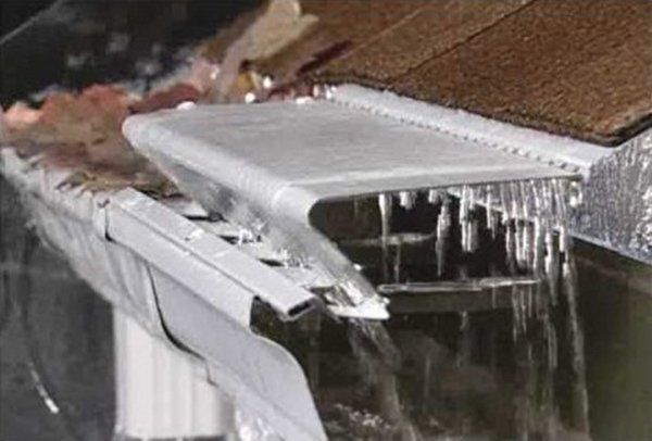 Icy gutter with a metal guard, water flowing. 