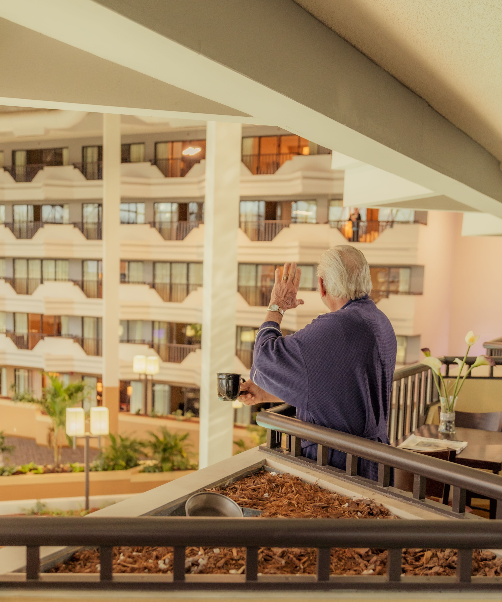 A man standing on a balcony looking out at a building