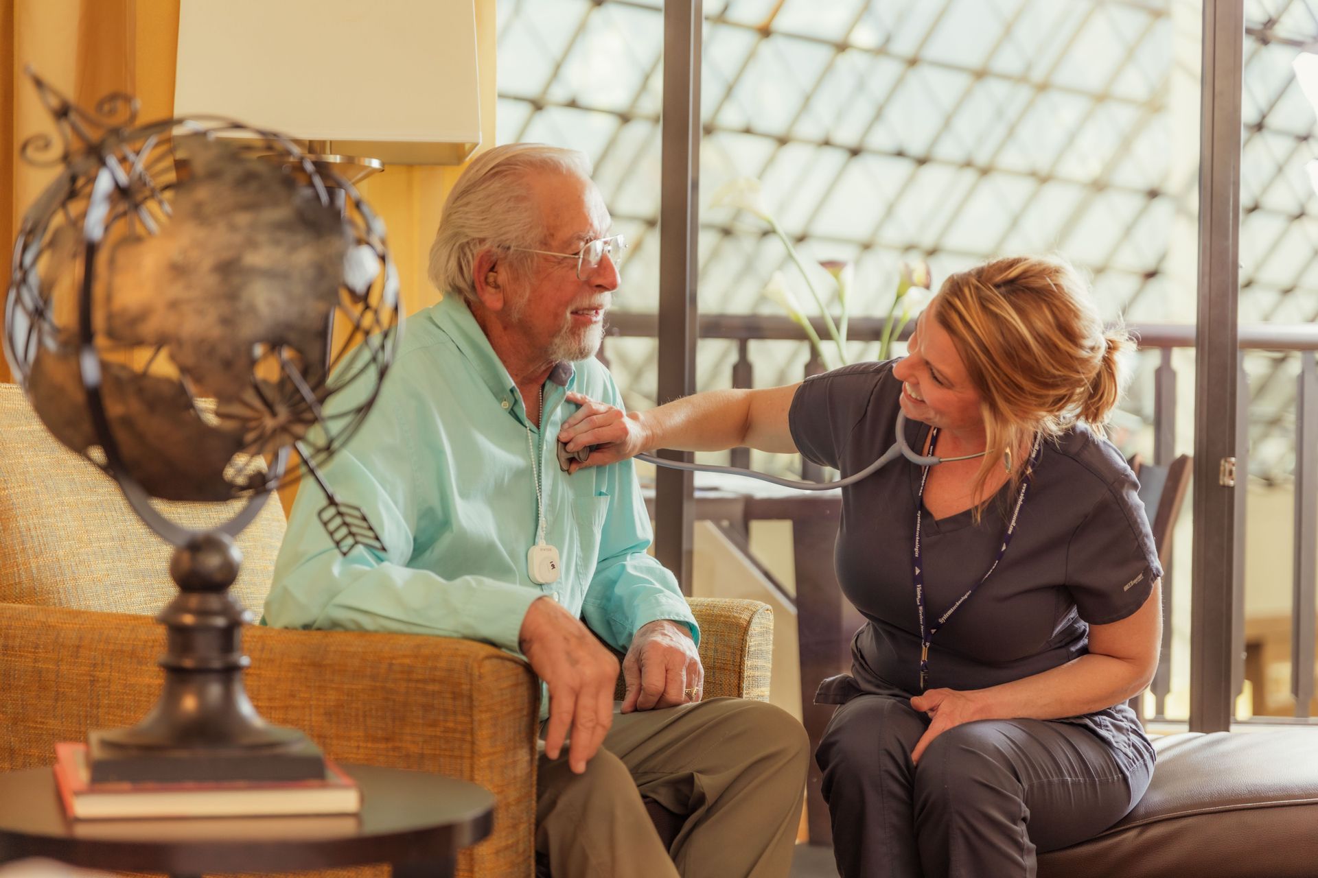 A nurse is examining an elderly man 's heartbeat with a stethoscope.