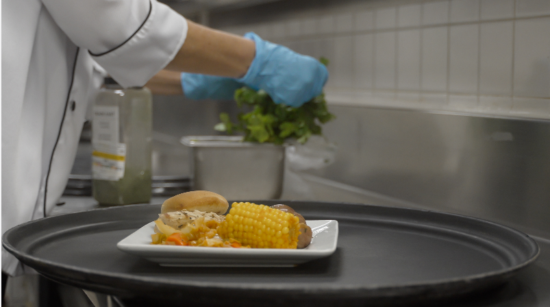A chef is putting a plate of food on a tray in a kitchen.