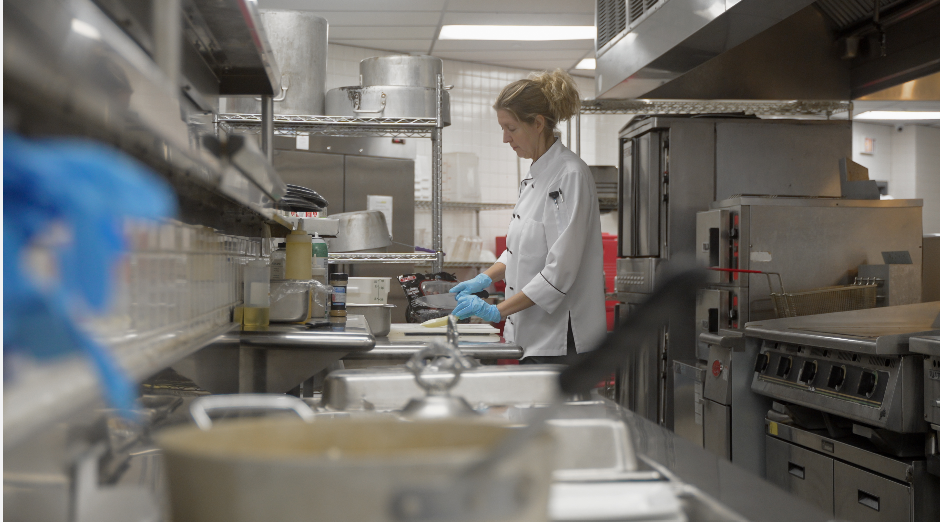A woman is standing in a kitchen preparing food.
