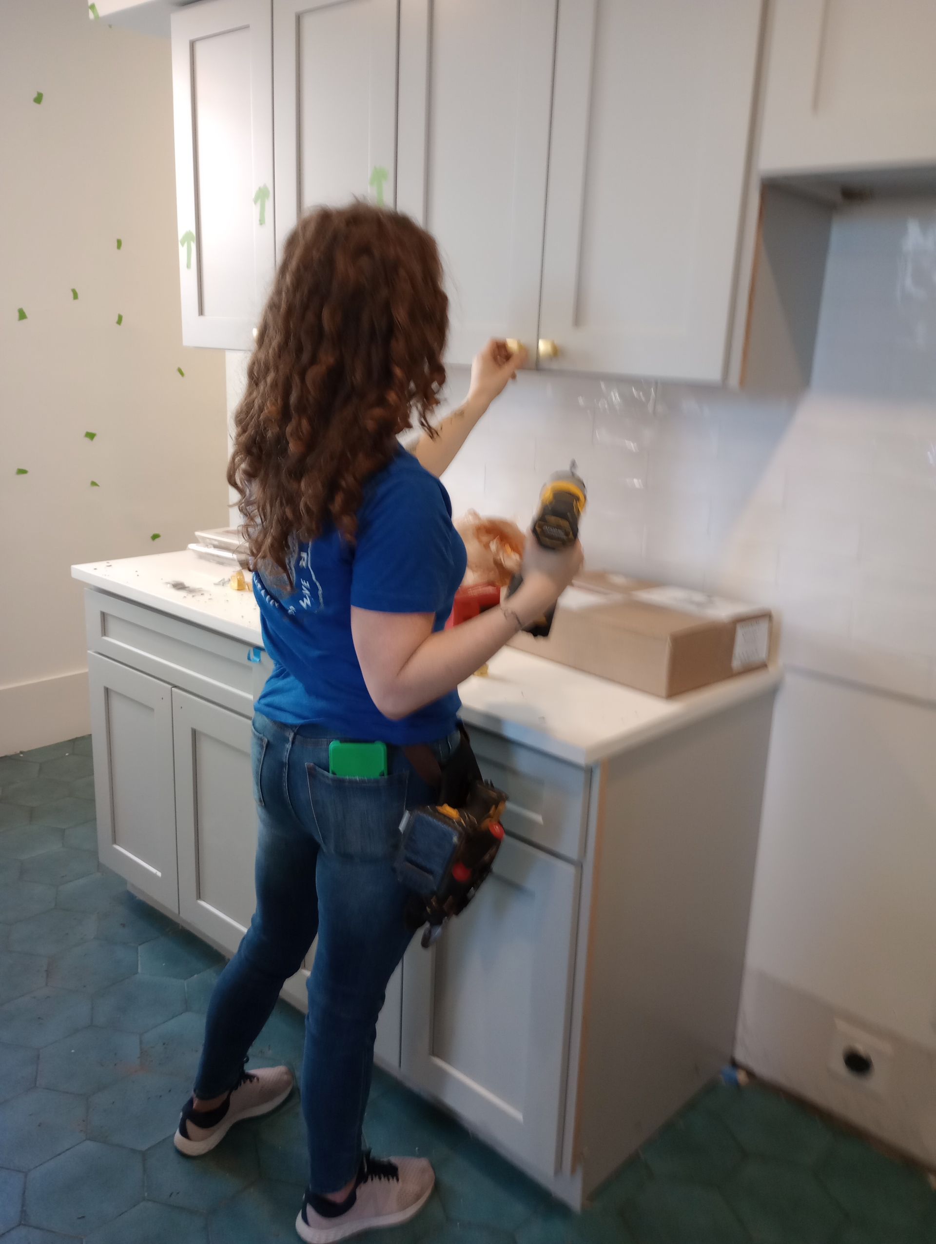 A woman in a blue shirt is working in a kitchen.