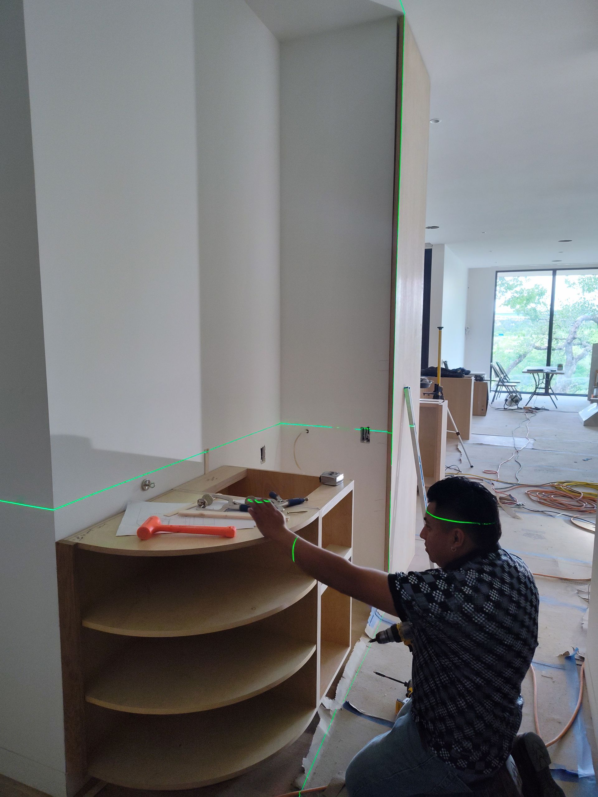 A man is measuring a shelf with a green laser.