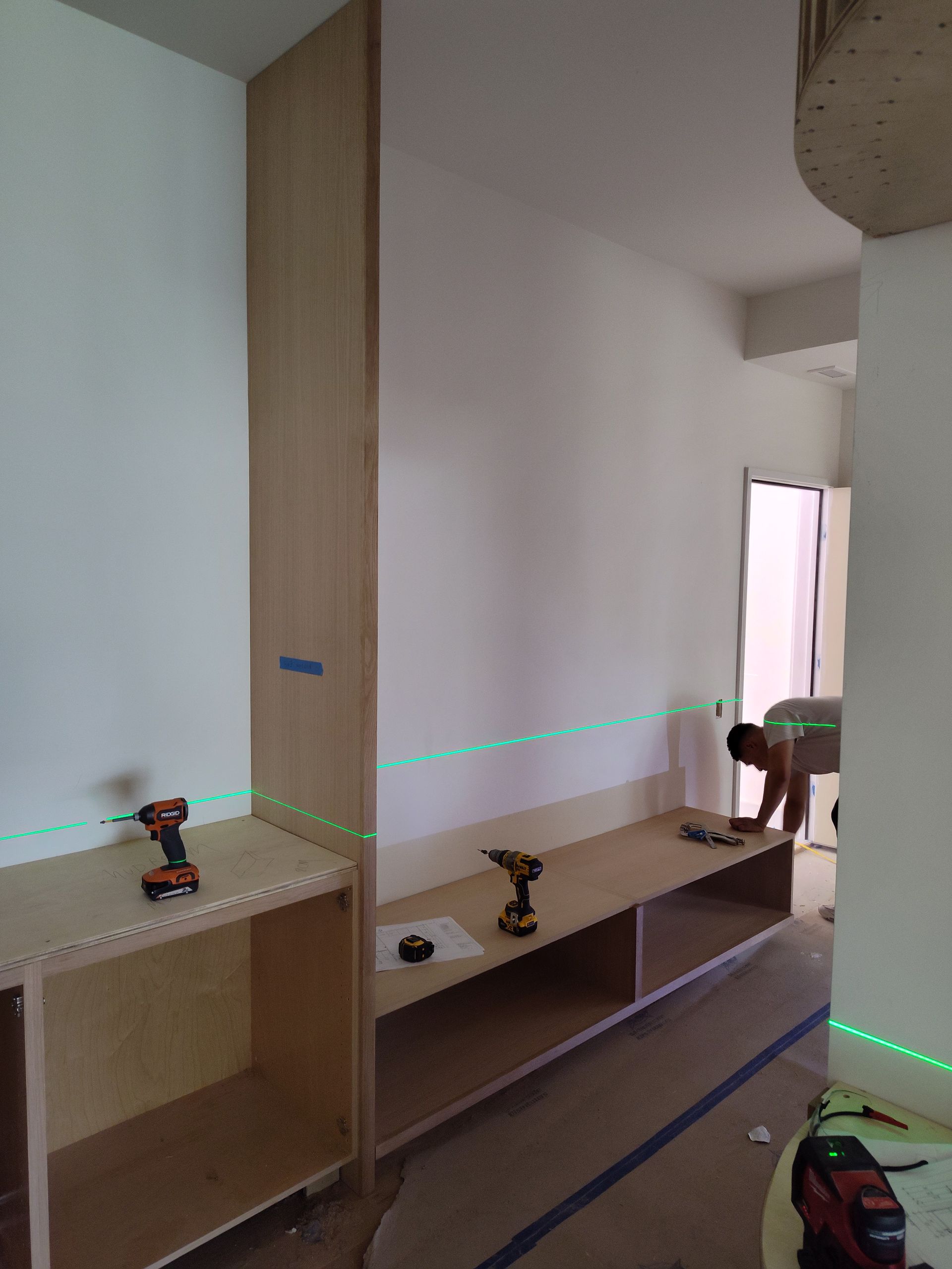 A man is working on a wooden shelf in a room.