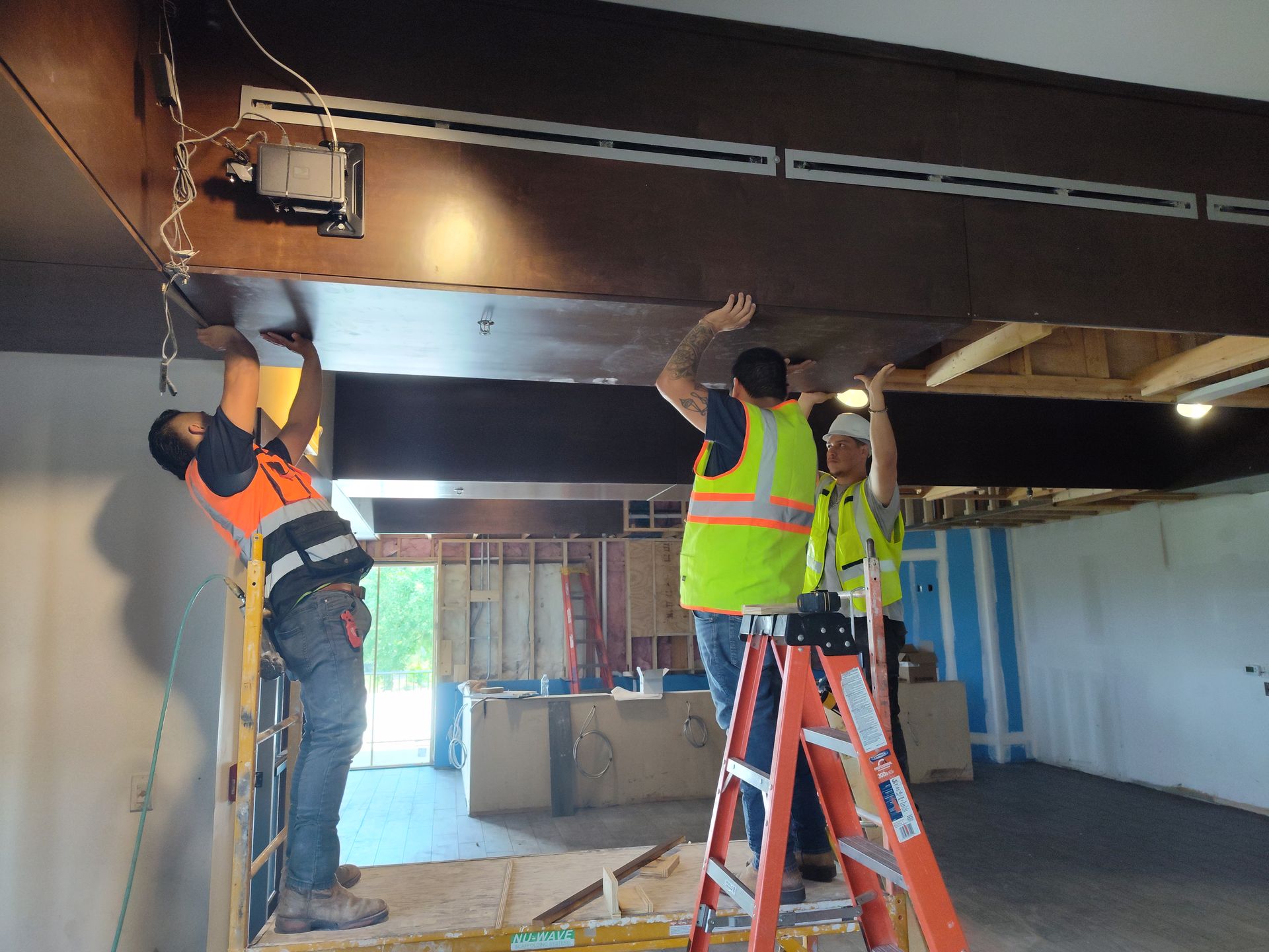 A group of construction workers are working on the ceiling of a building.