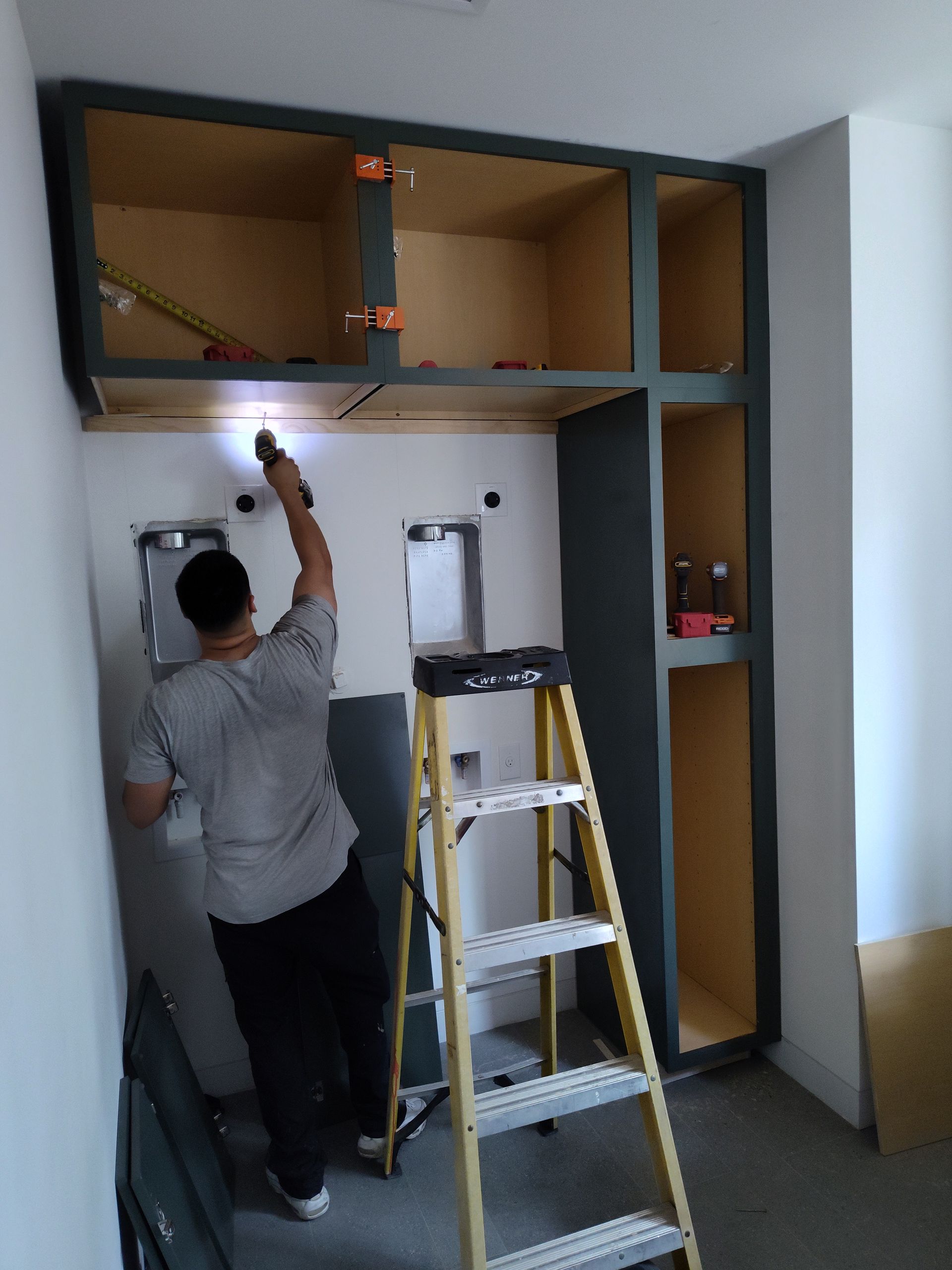 A man standing on a ladder working on a wall.
