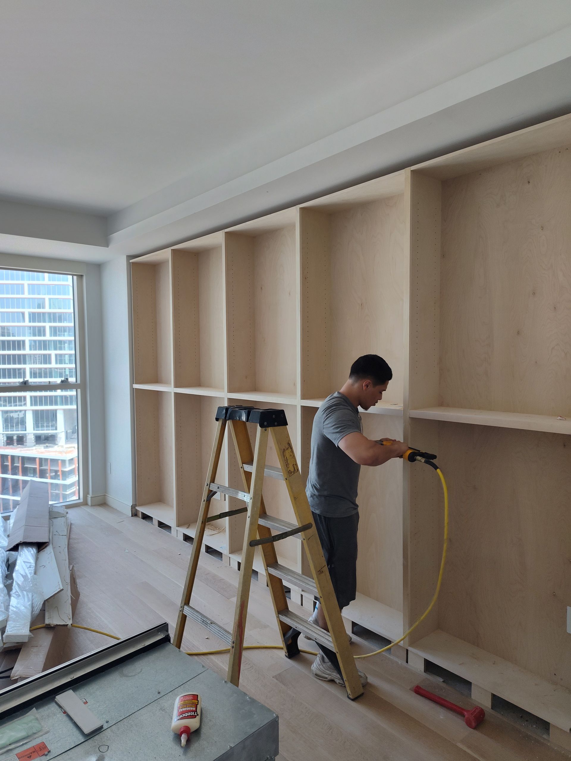 A man standing on a ladder working on a wall.