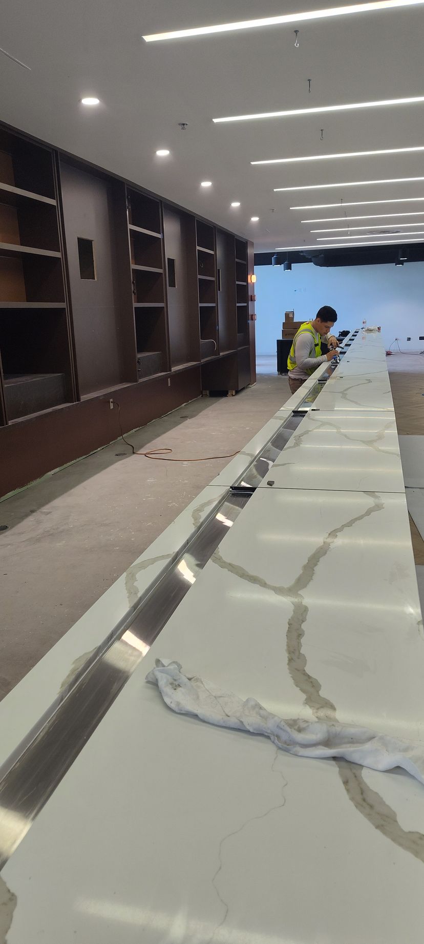 A man is working on a long table in a large room.