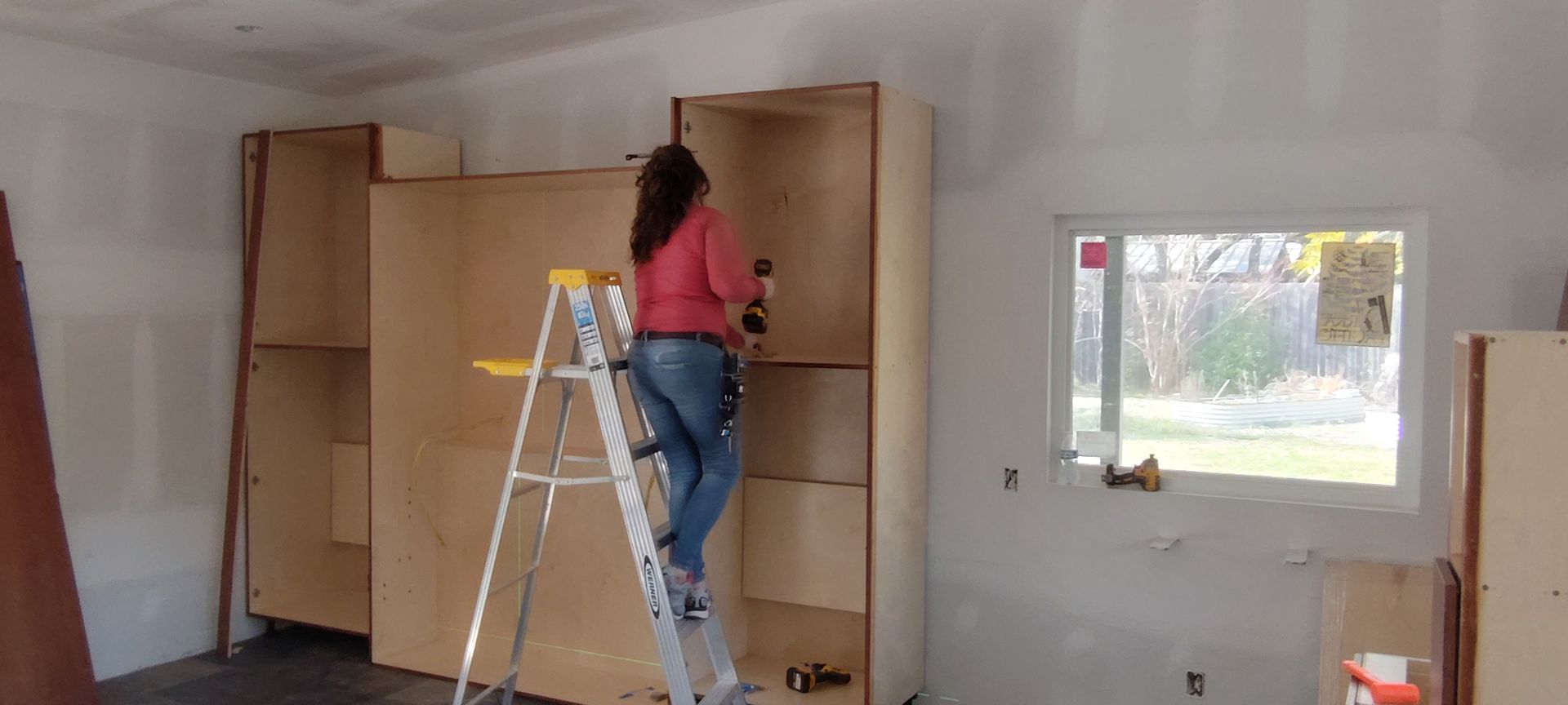 A woman is standing on a ladder in a room.