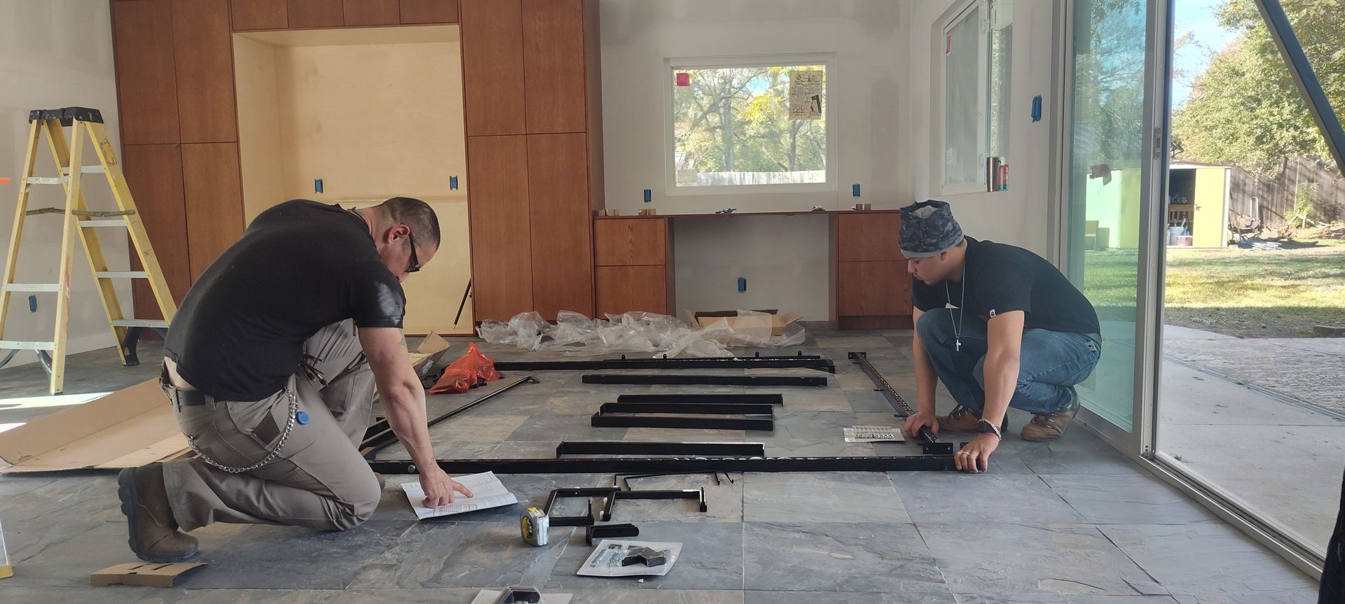 Two men are working on a floor in a room.