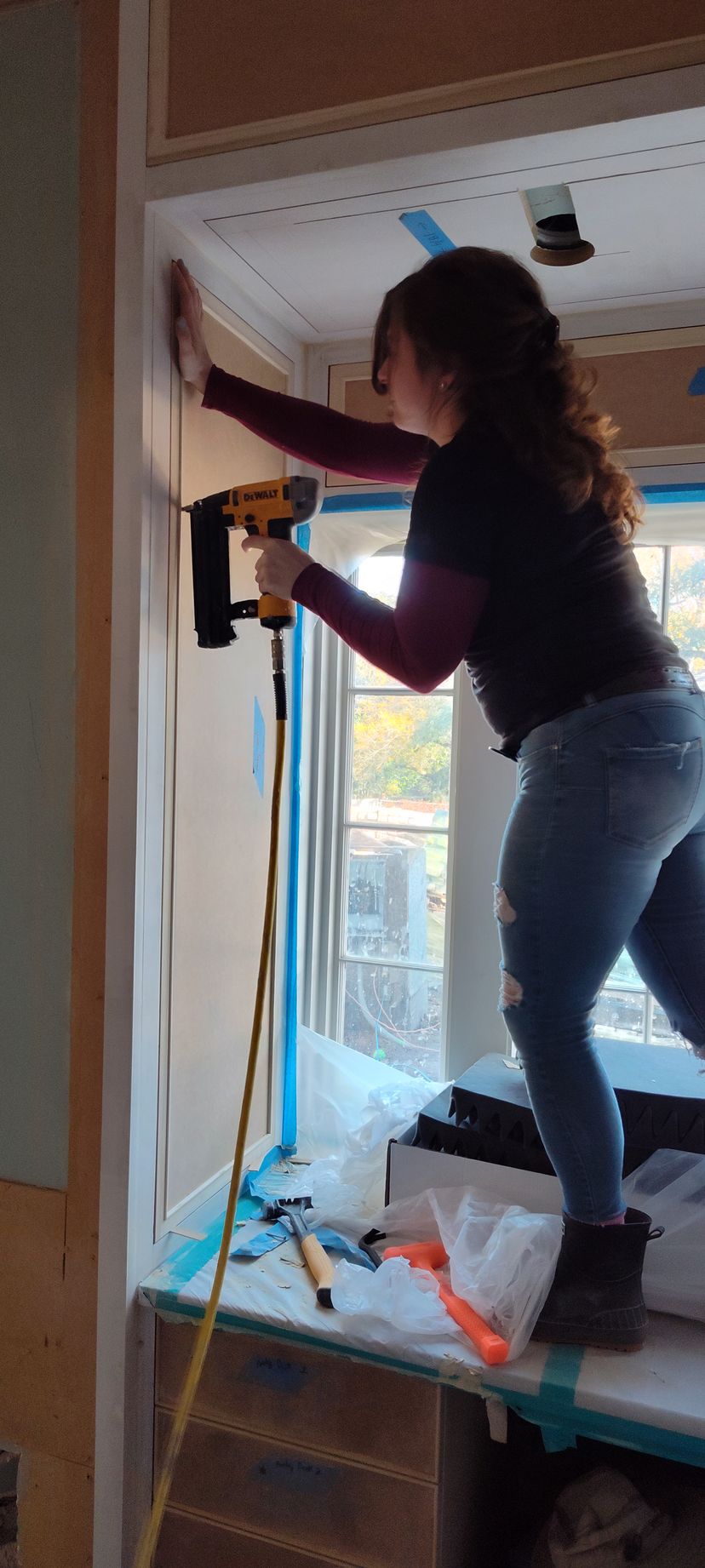 A woman standing working on a wall.