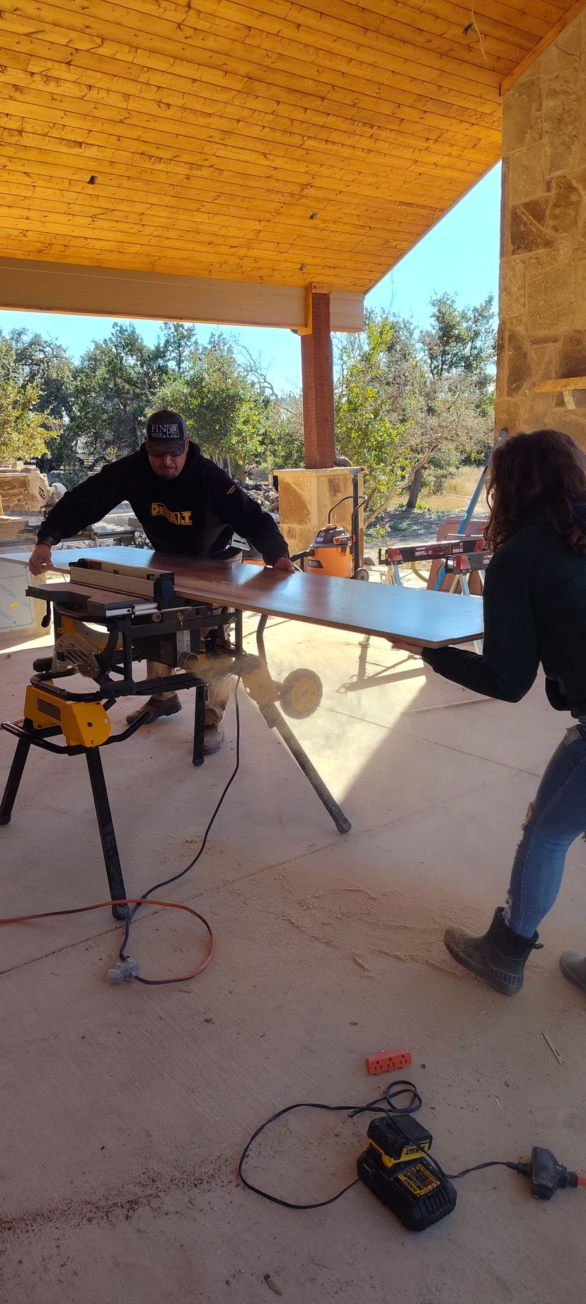 A man and a woman are working on a table saw.