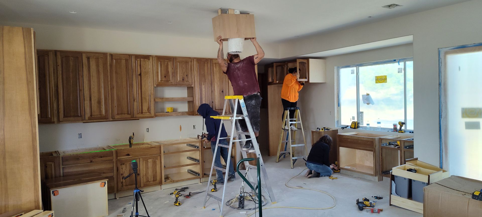 A group of men are working on a kitchen in a house.