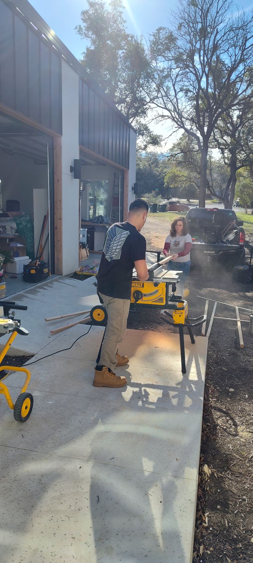 A man is standing next to a table saw in a garage.